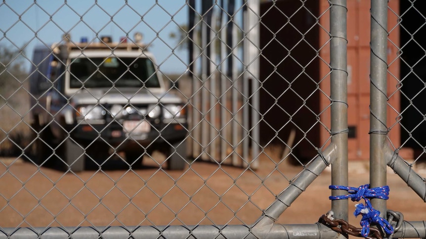 A large padlock secures the gate of the police station.