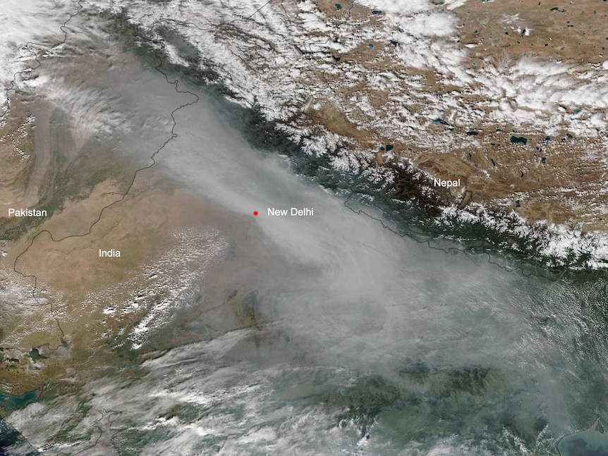 A satellite image shows a dense layer of grey smog over Northern India looming larger than white clouds.