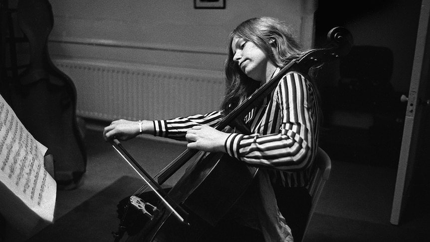Jacqueline Du Pré practising and a black and white striped shirt.
