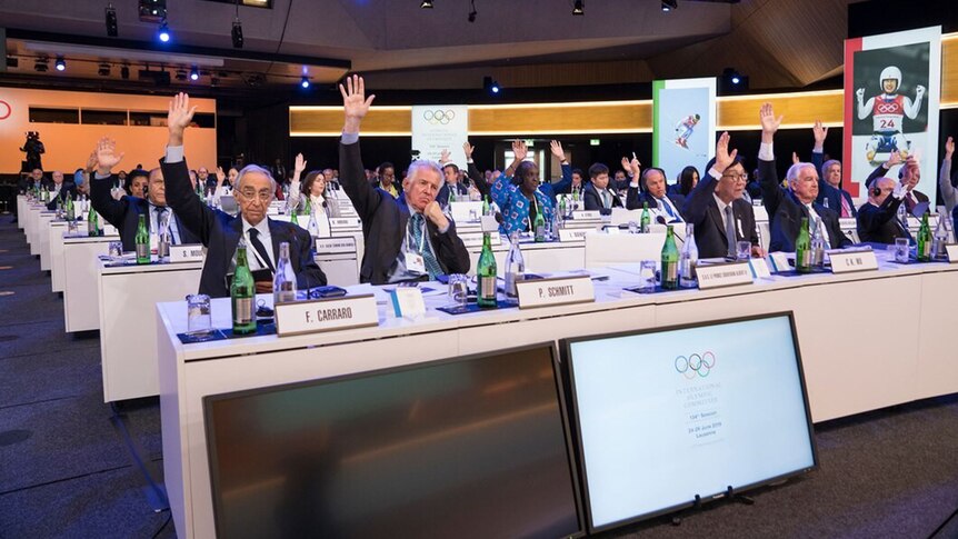 Several officials raises their hands at a meeting of the International Olympic Committee in Switzerland