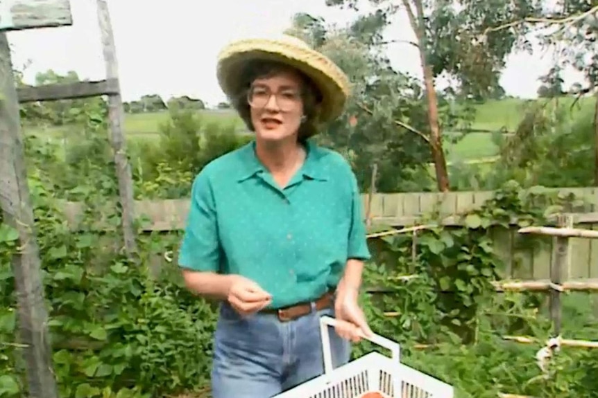Edmanson wearing hat holding basket in garden.