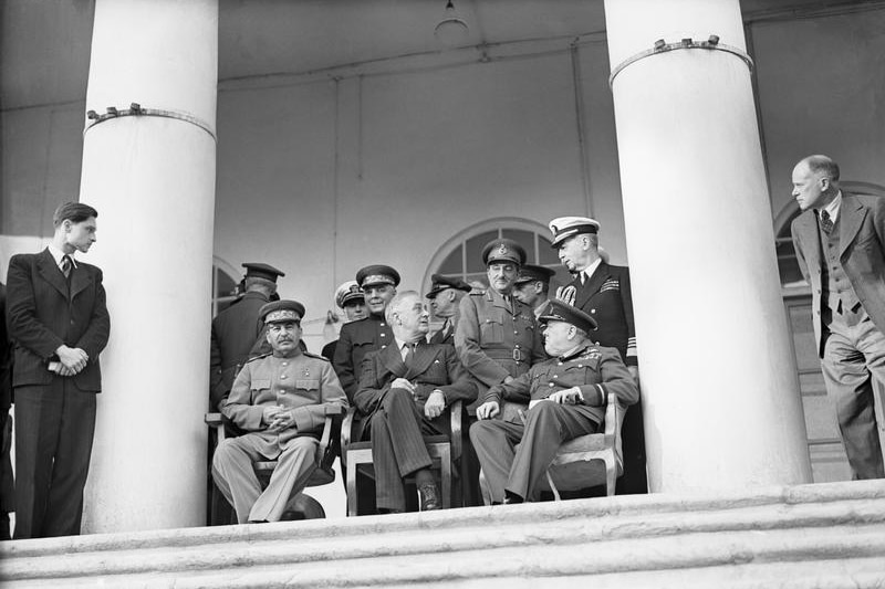 A historical photo of Winston Churchill, Franklin Roosevelt and Joseph Stalin with other men at the Tehran Conference in 1943.