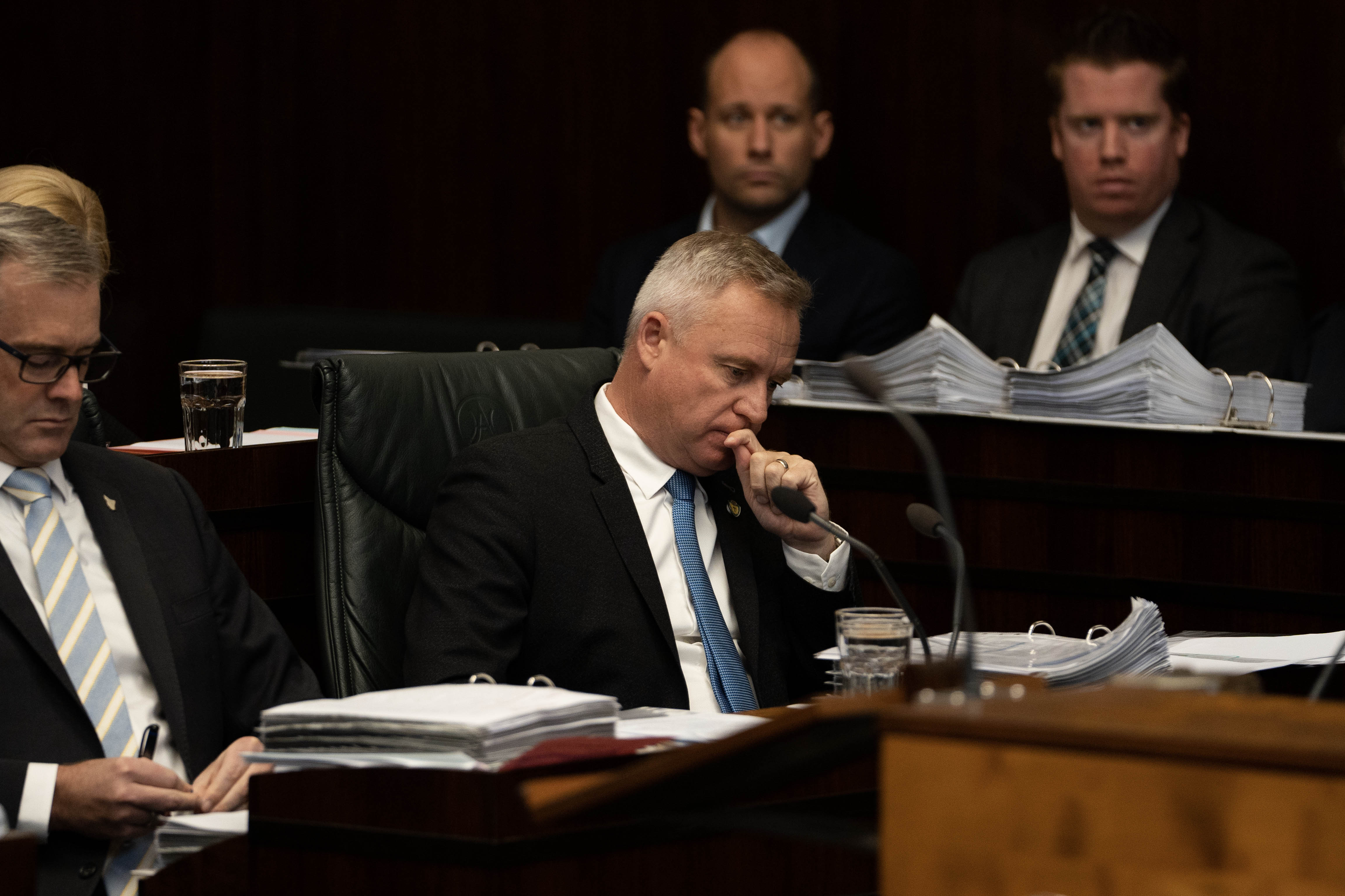 Jeremy Rockliff appears to be in thought, surrounded by his colleagues.