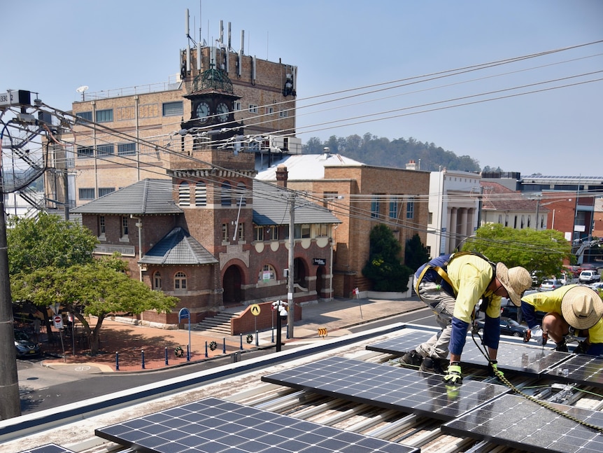 Workers install solar panels on a flat roof
