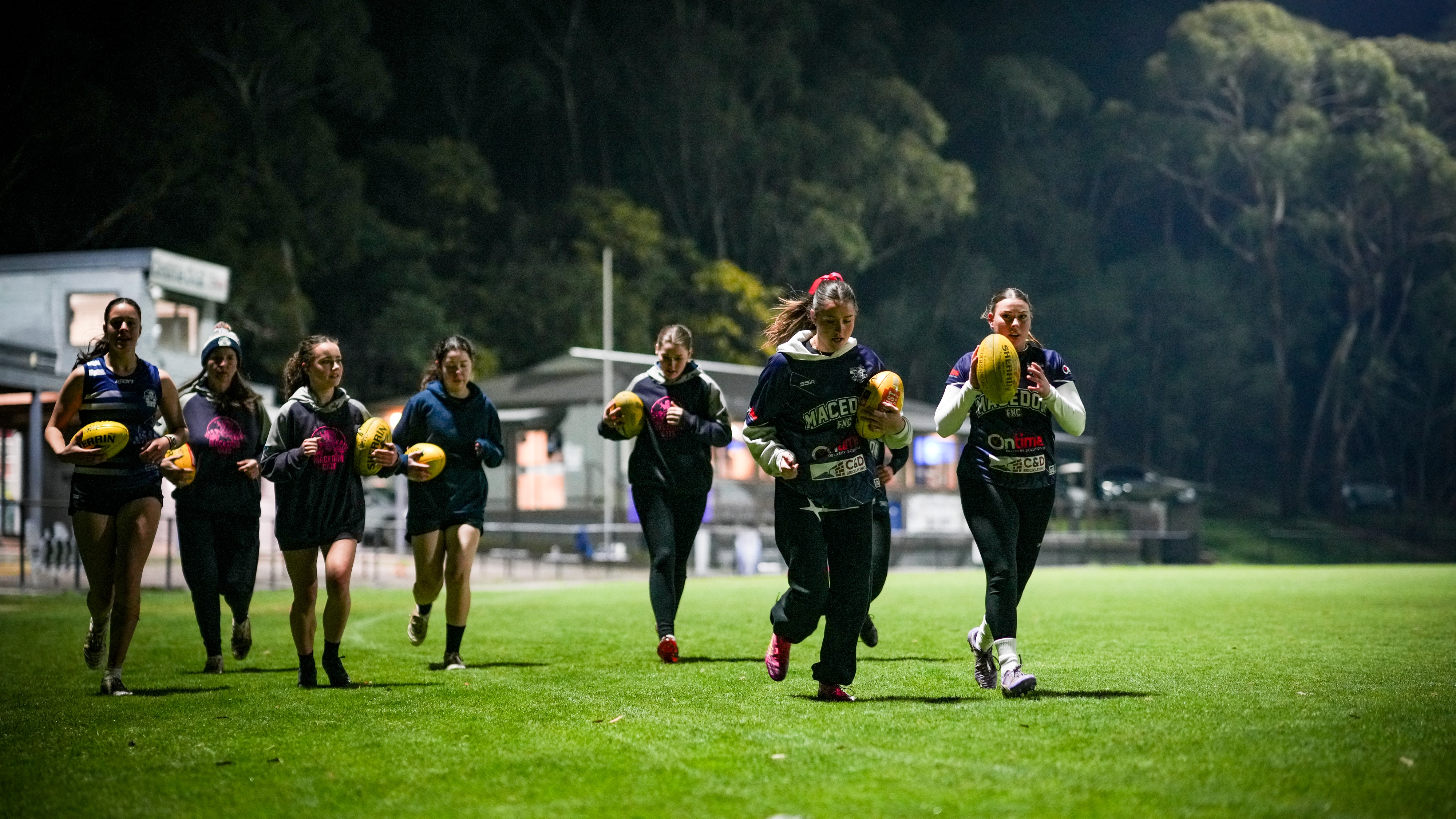 A women's football team, running with balls.