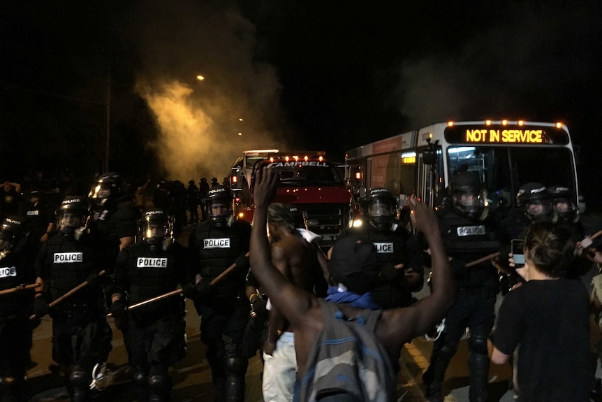 Police gather around protestors on a street.