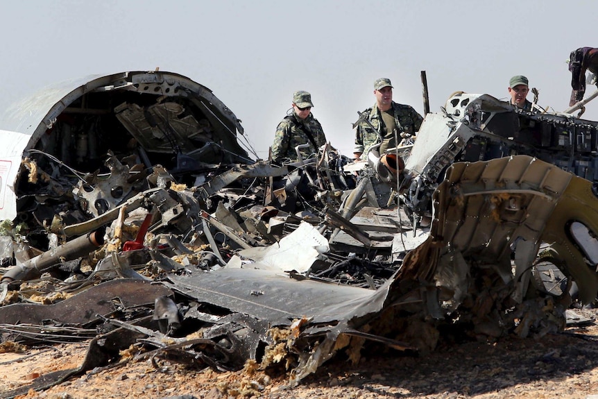 Russian military investigators stand near the debris of a Kogalymavia airlines plane that crashed in Egypt.