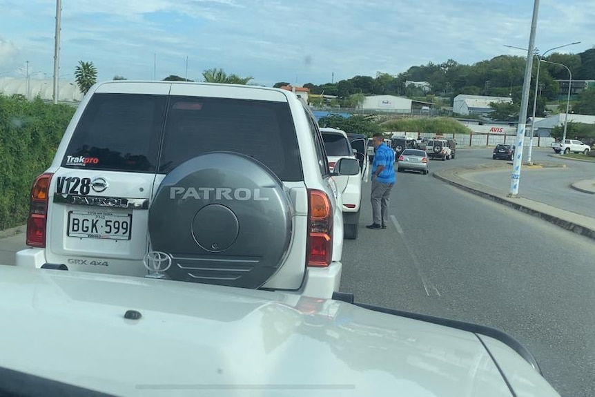 A man stands next to a car in the middle of a traffic jam