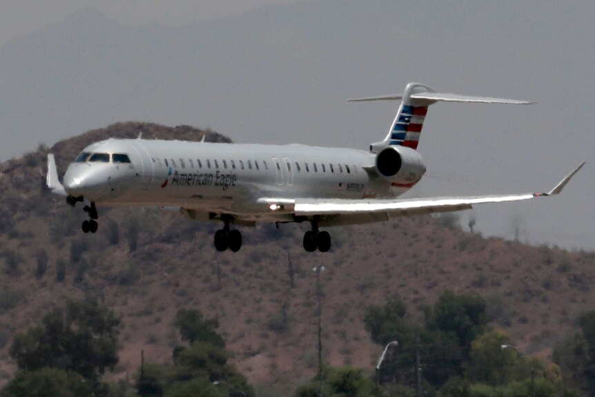 An image of a plane landing is rippled by heatwaves, there is a dry-looking mountain behind the plane.