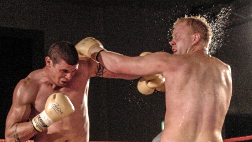 Two men fight in a boxing ring.