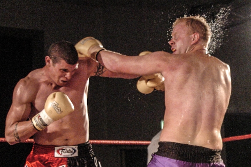 Two men fight in a boxing ring.