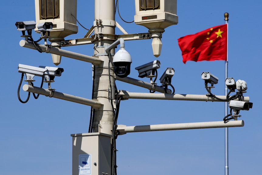 A Chinese national flag flutters near the surveillance cameras mounted on a lamp post in Tiananmen Square in Beijing.