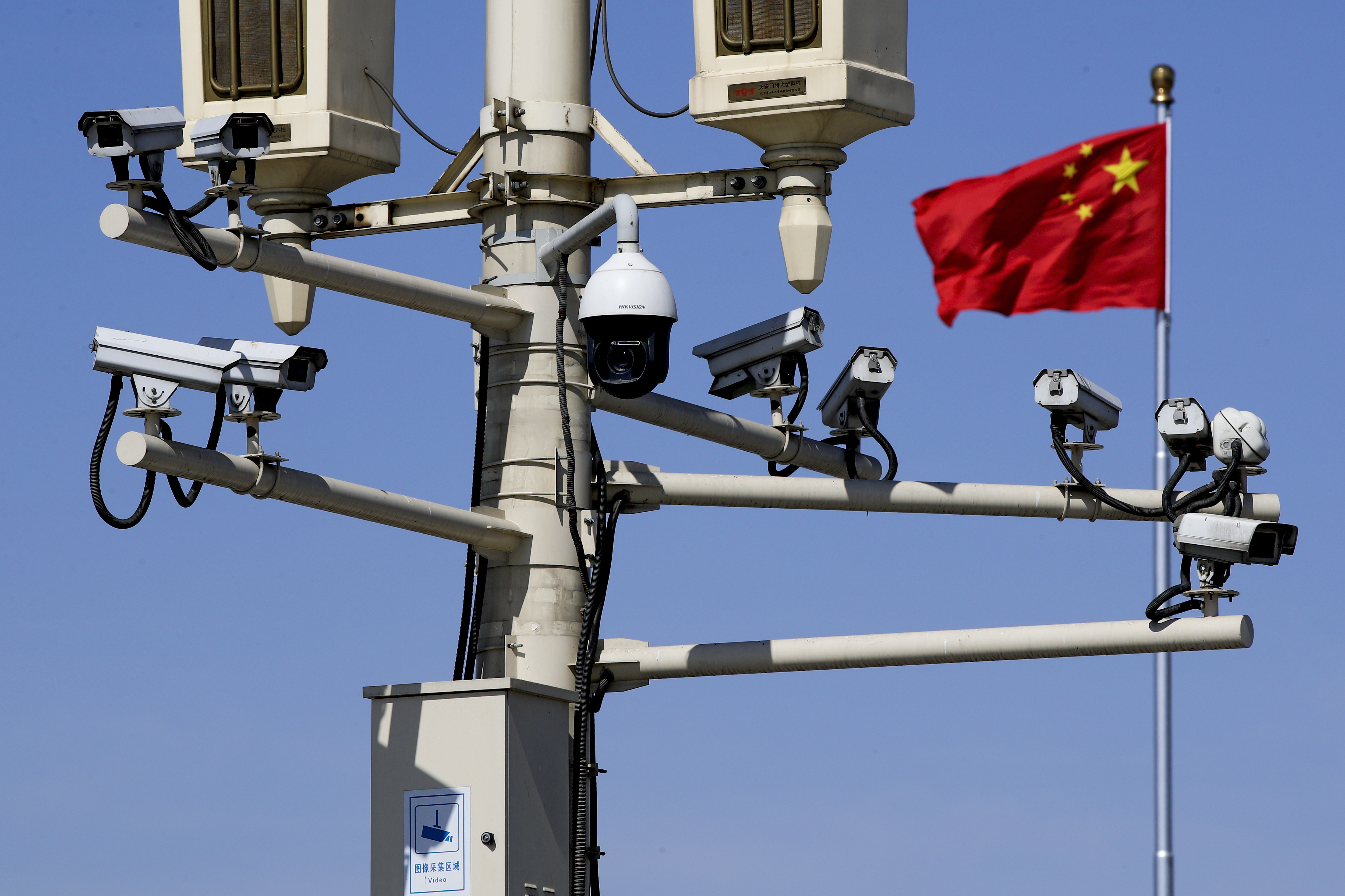 中国国旗在北京天安门广场灯柱上的监控摄像头附近飘扬。