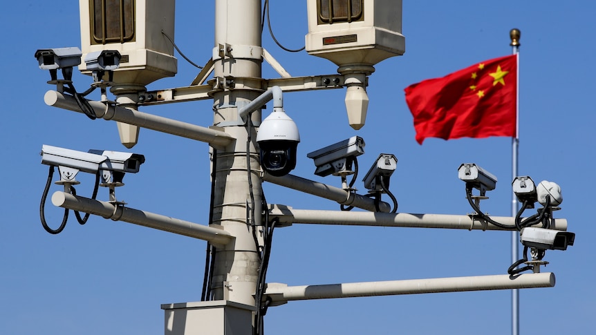 A Chinese national flag flutters near the surveillance cameras mounted on a lamp post in Tiananmen Square in Beijing.