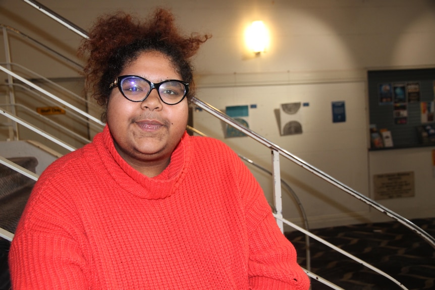 A woman in a red jumper smiling at a camera.