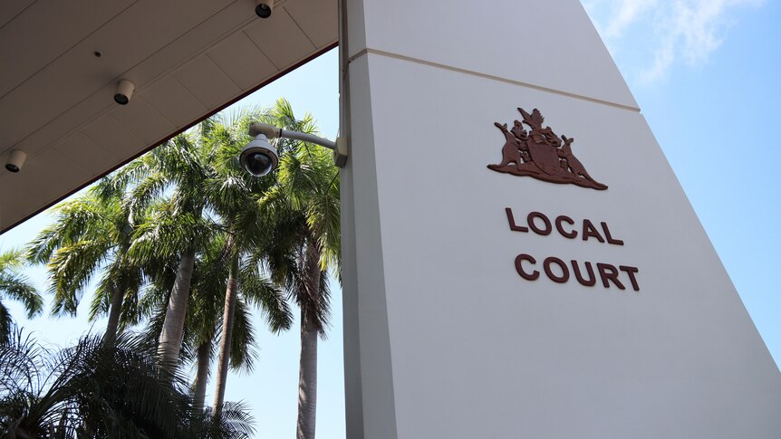 The entrance of the Darwin Local Court, on a sunny day. There are palm trees and blue sky in the background.