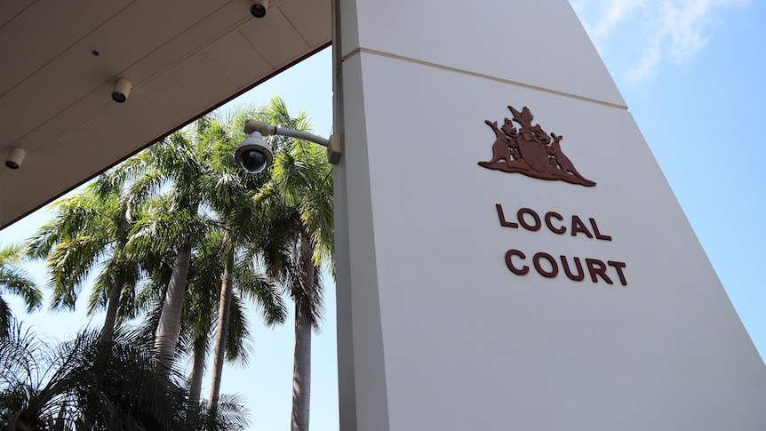 The entrance of the Darwin Local Court, on a sunny day. There are palm trees and blue sky in the background.