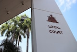 The entrance of the Darwin Local Court, on a sunny day. There are palm trees and blue sky in the background.