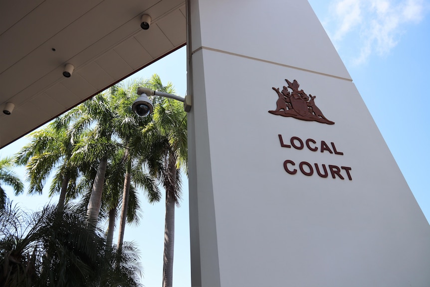 The entrance of the Darwin Local Court, on a sunny day. There are palm trees and blue sky in the background.