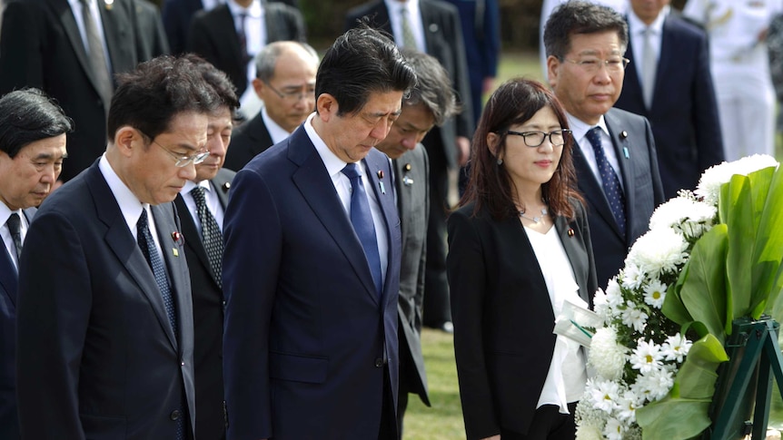 Shinzo Abe stands with his head bowed at the Ehime Maru Memorial at Kakaako Waterfront Park.