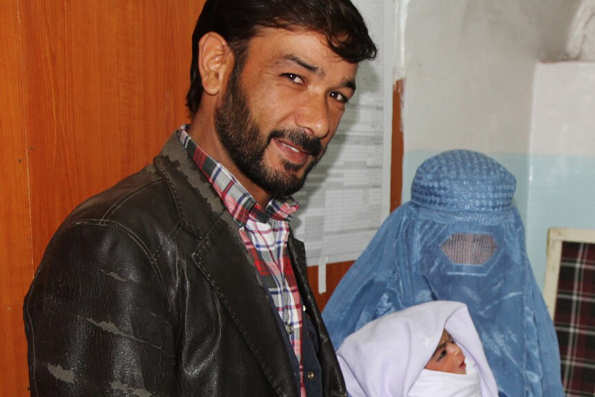 Afghan couple with their adopted baby girl who was rescued by Polish troops