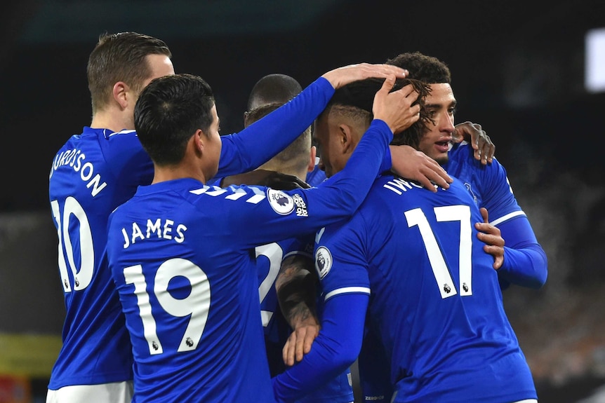 Everton players, wearing blue shirts with white chevrons on the sleeves and white numbers, hug