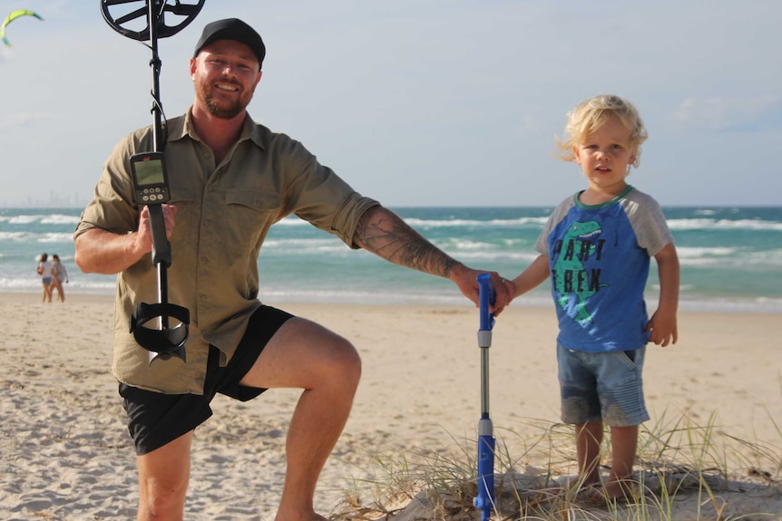 Amateur detectorist Murray Beattie and son Taj on a beach with metal detectors