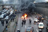 Anti-riot policemen arrive as taxi drivers block the traffic with a fire during a demonstration.