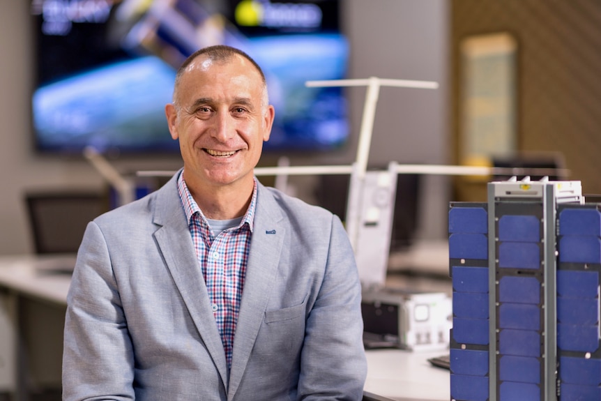 a man smiles at the camera sitting in a lab