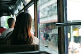 A photo of the backs of people's heads sitting on a bus.