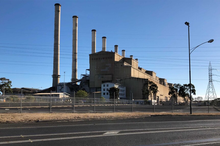 A large power station behind a cyclone fence with eight chimneys