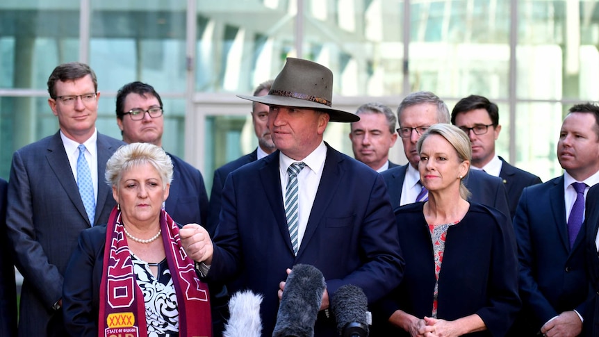 Barnaby Joyce, wearing an akubra, stands in front of his Nationals colleagues.