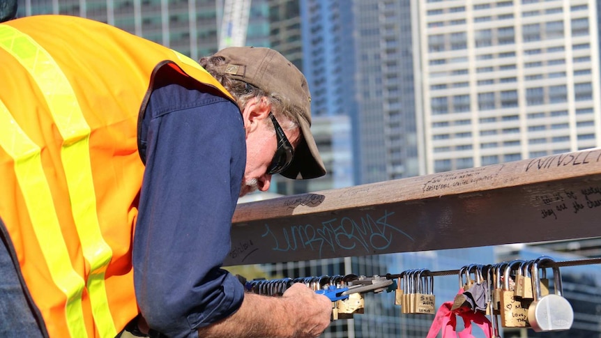 A Melbourne City Council worker removes thousands of padlocks from Southgate footbridge.