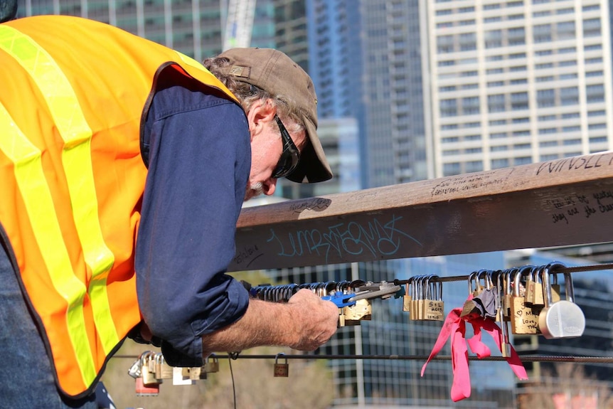 A Melbourne City Council worker removes thousands of padlocks from Southgate footbridge.