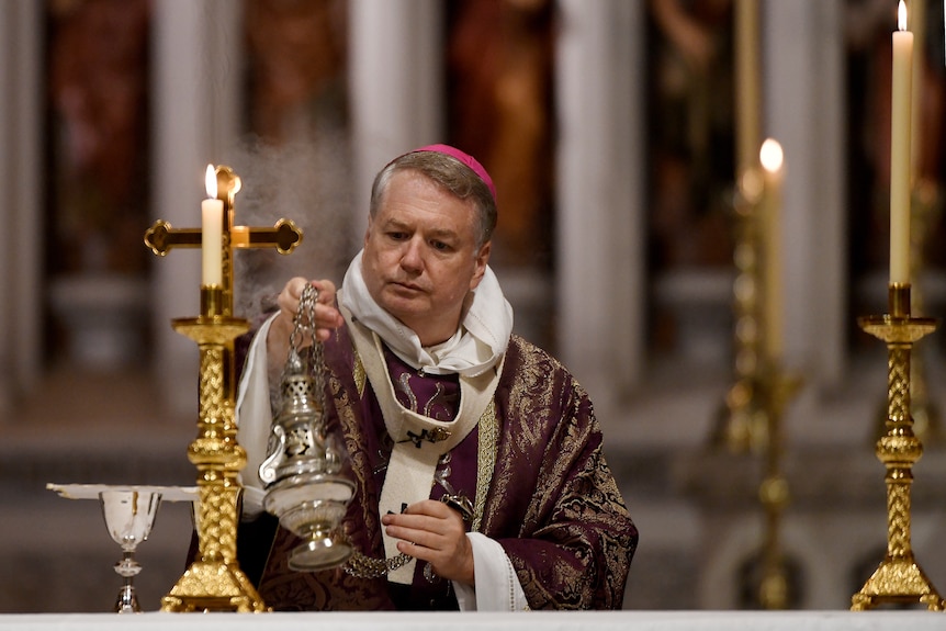 Archbishop Anthony Fisher holds a censer during a Catholic mass