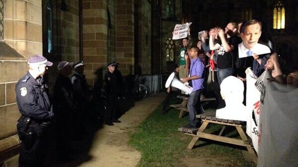 Police stand in front of protesters outside a Liberal Club debate at Sydney University