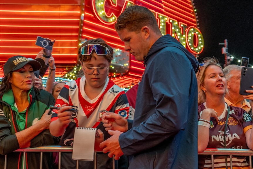 Amongst the bright lights of Las Vegas, a player signs an autograph as fans crowd around.