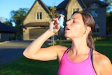 Mid shot of sportswoman holding asthma puffer near her mouth