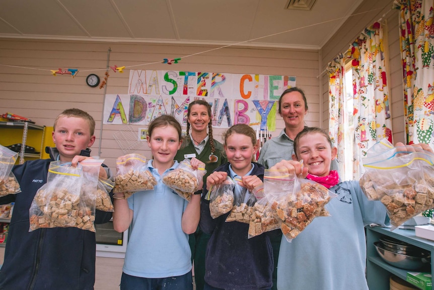 Primary school kids stand proud with their bags of Bogong biscuits.
