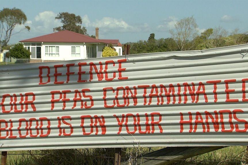 A sign critical of the Australian Defence Force near a farm house.