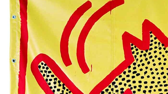 Colour photograph of iconic Keith Haring character outlined in red with black dot filling outline on canvas.