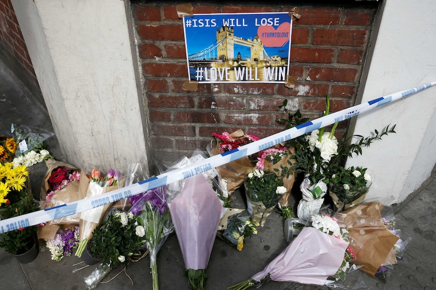 Flowers and messages lie behind police cordon tape near Borough Market after an attack left seven people dead in London.