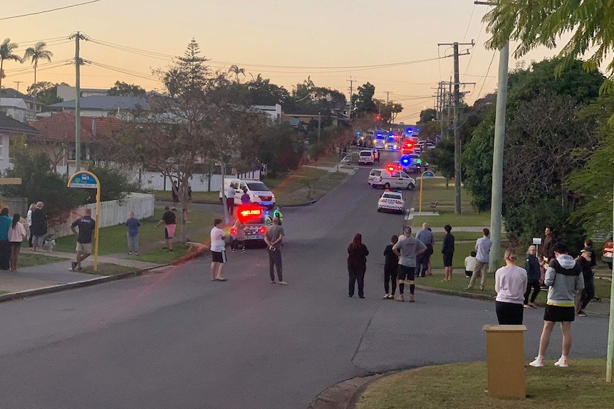 Neighbours on a street watching a police operation underway