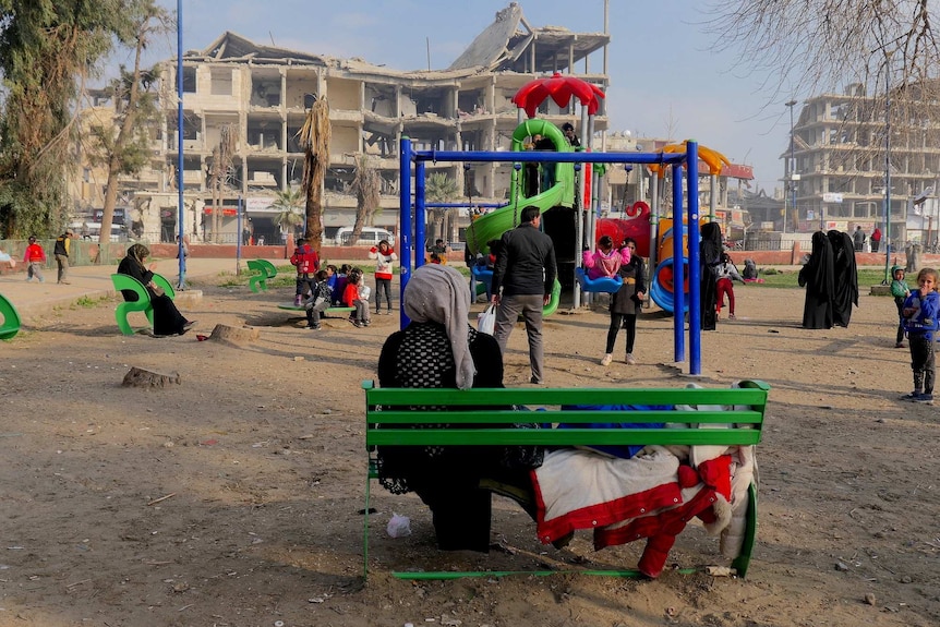 A woman watches children use a playground