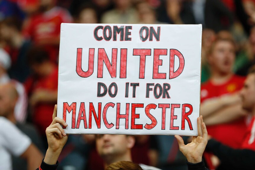 Manchester United fan with a banner in tribute to the victims of the Manchester attack