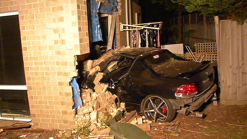A car is seen crashed into a house.