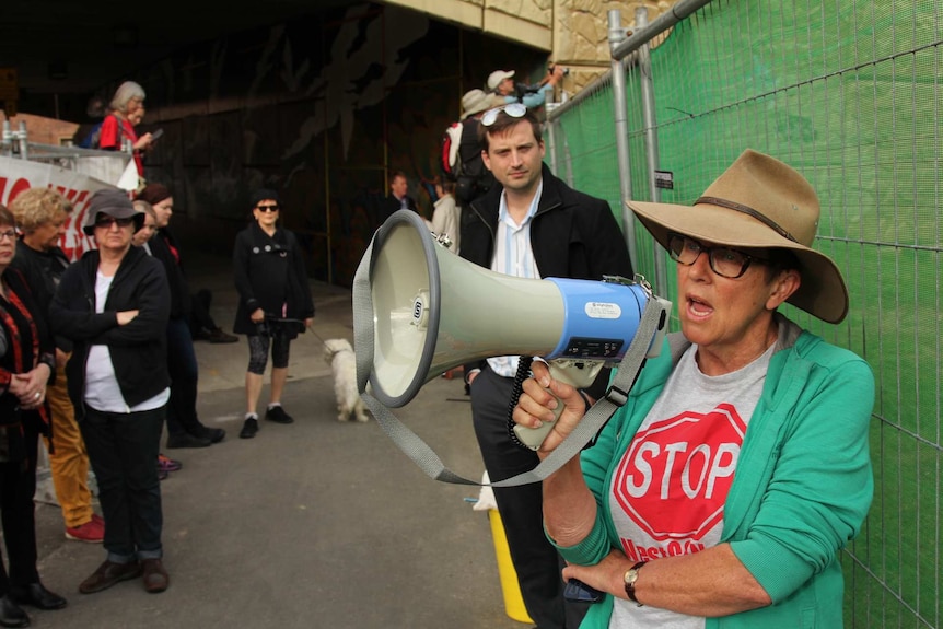 A woman speaks through a megaphone at a crowd.