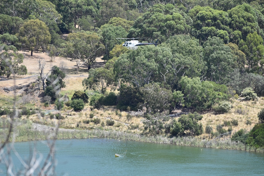 a helicopter flying above a lake