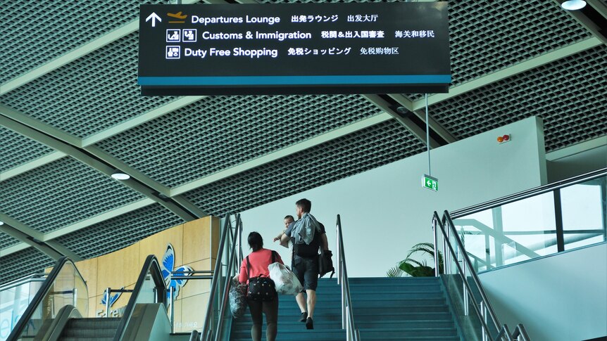 A family climbs the stairs towards an airport departure lounge.
