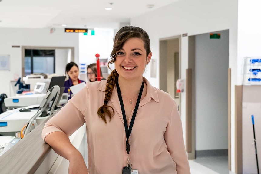 Rachel Middleton stands in the corridor in the Gorman unit at St Vincent's Hospital, she is wearing a pink blouse and smiling.